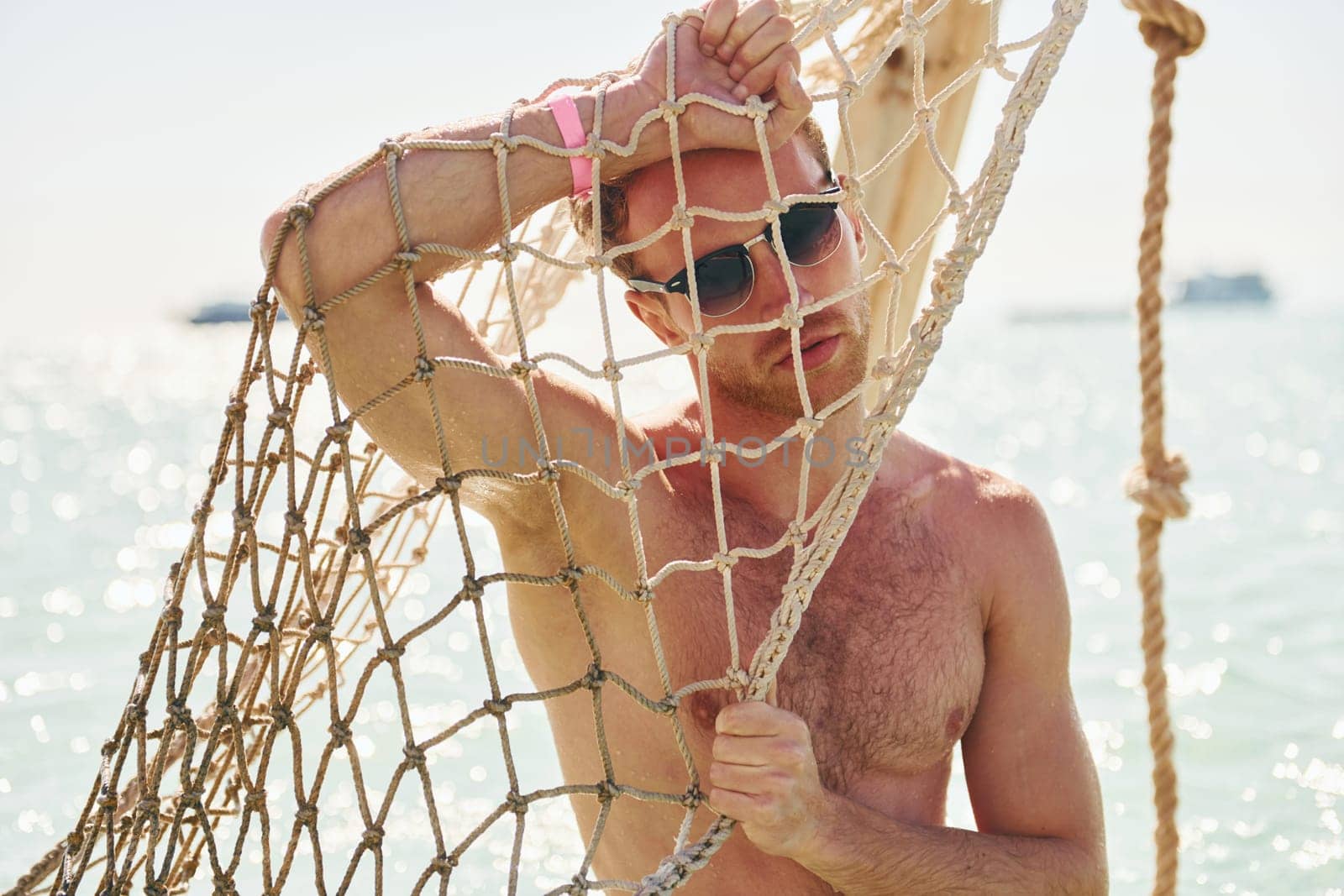 Warm weather. Young european man have vacation and enjoying free time on the beach of sea by Standret