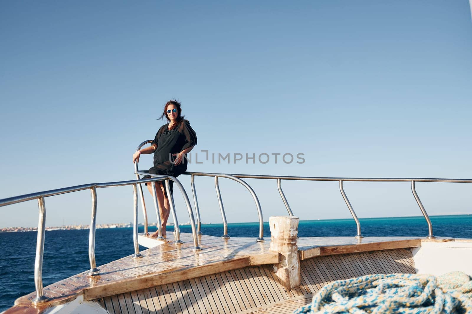 Mature woman standing on the yacht and enjoying her vacation on the sea.