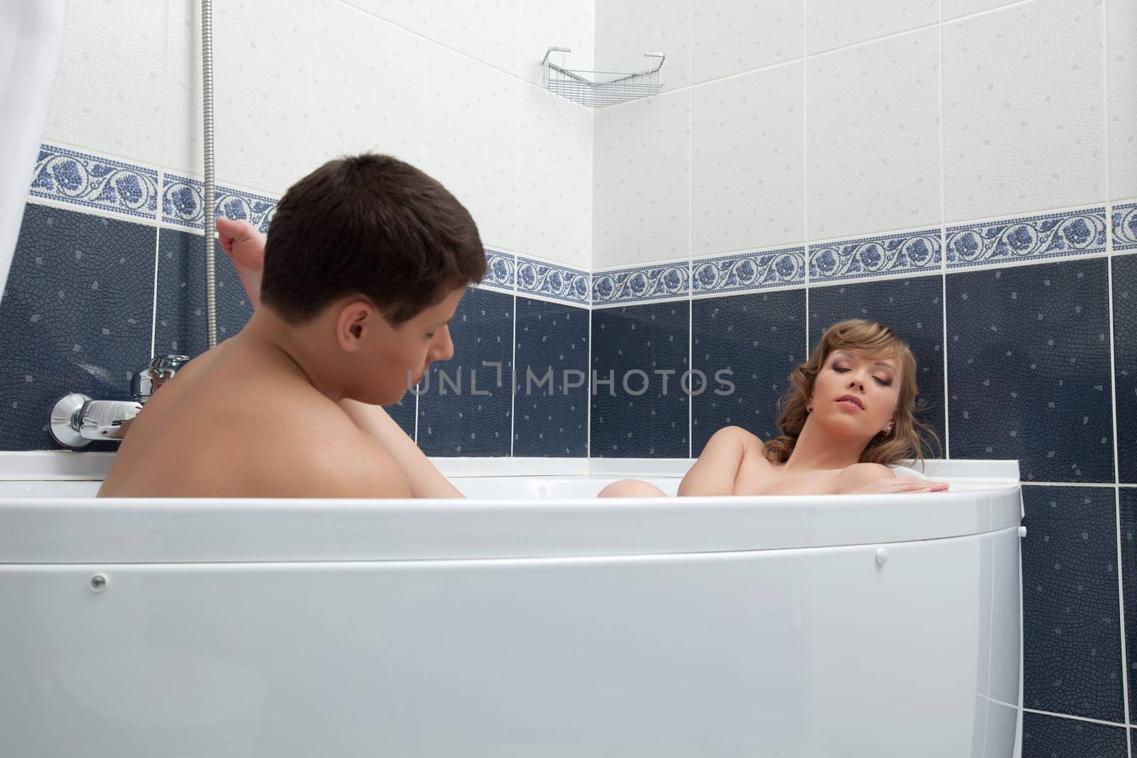 Portrait of sexy couple lay in bath and doing massage