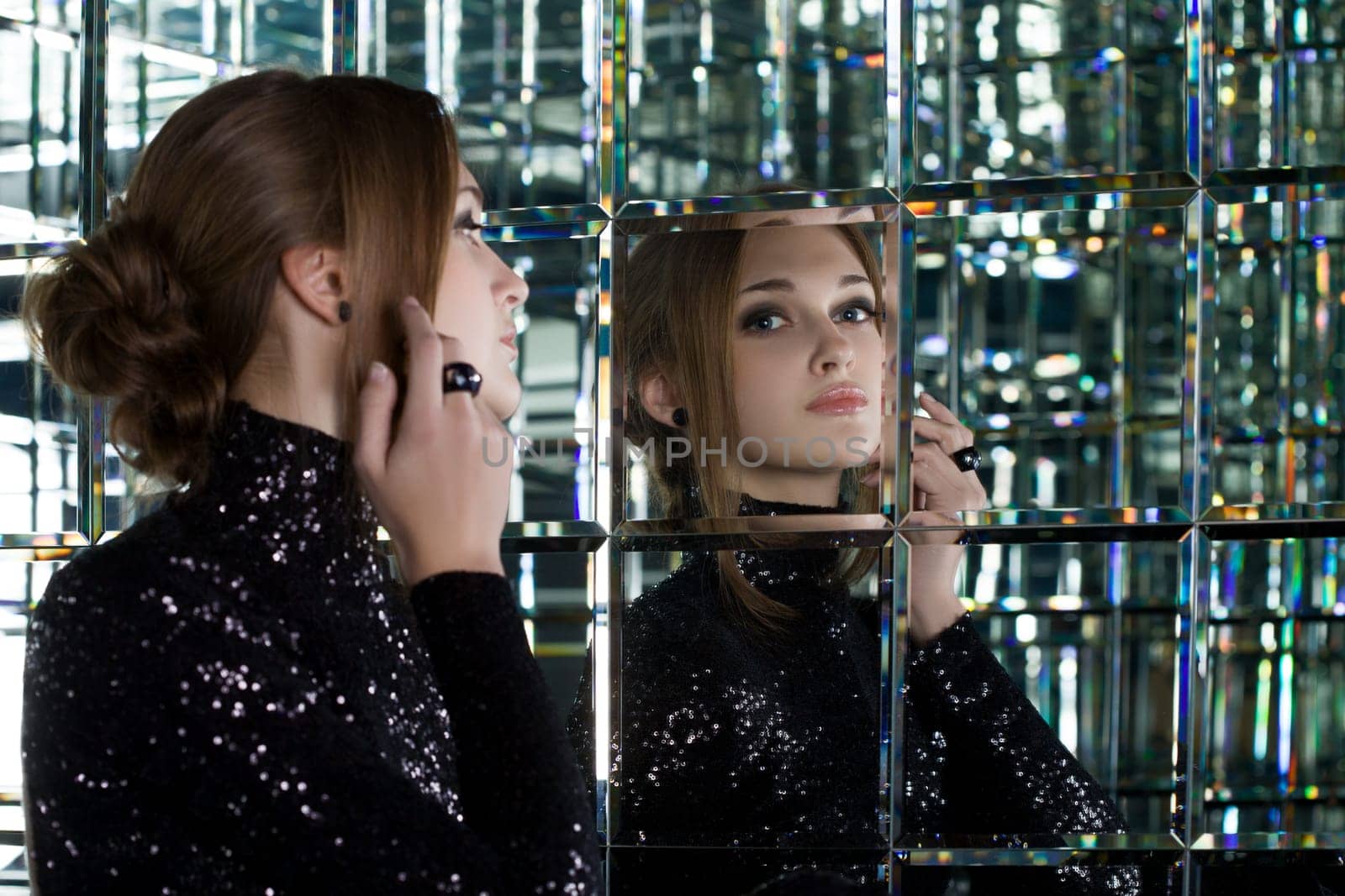 Full length portrait of beautiful young woman in long black dress near mirror