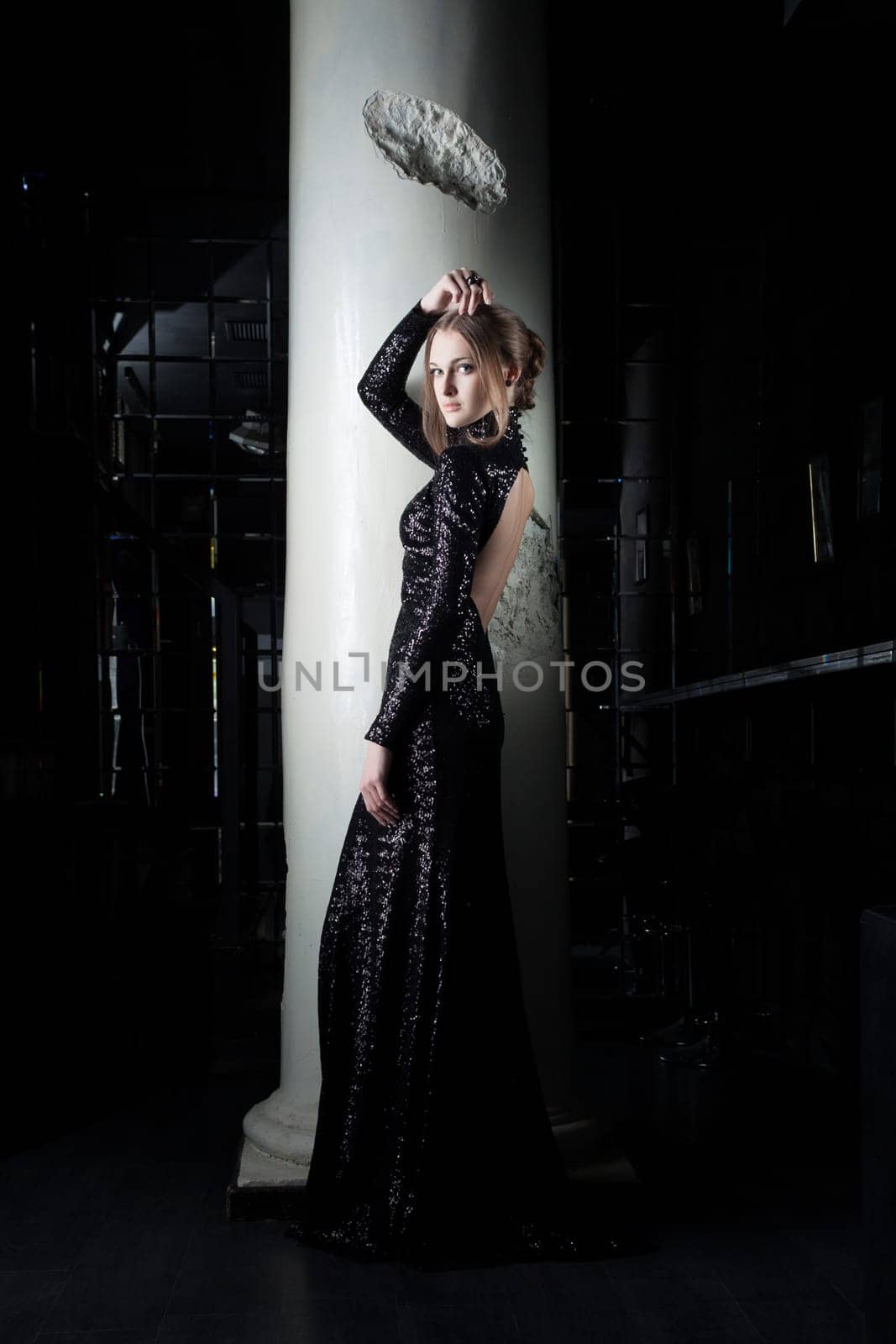 Full length portrait of beautiful young woman in black dress near column