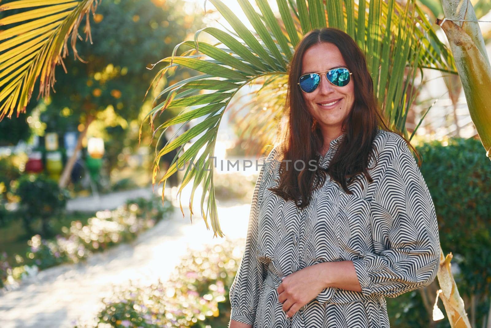 Happy mature woman is outdoors enjoying her vacation at sunny daytime by Standret