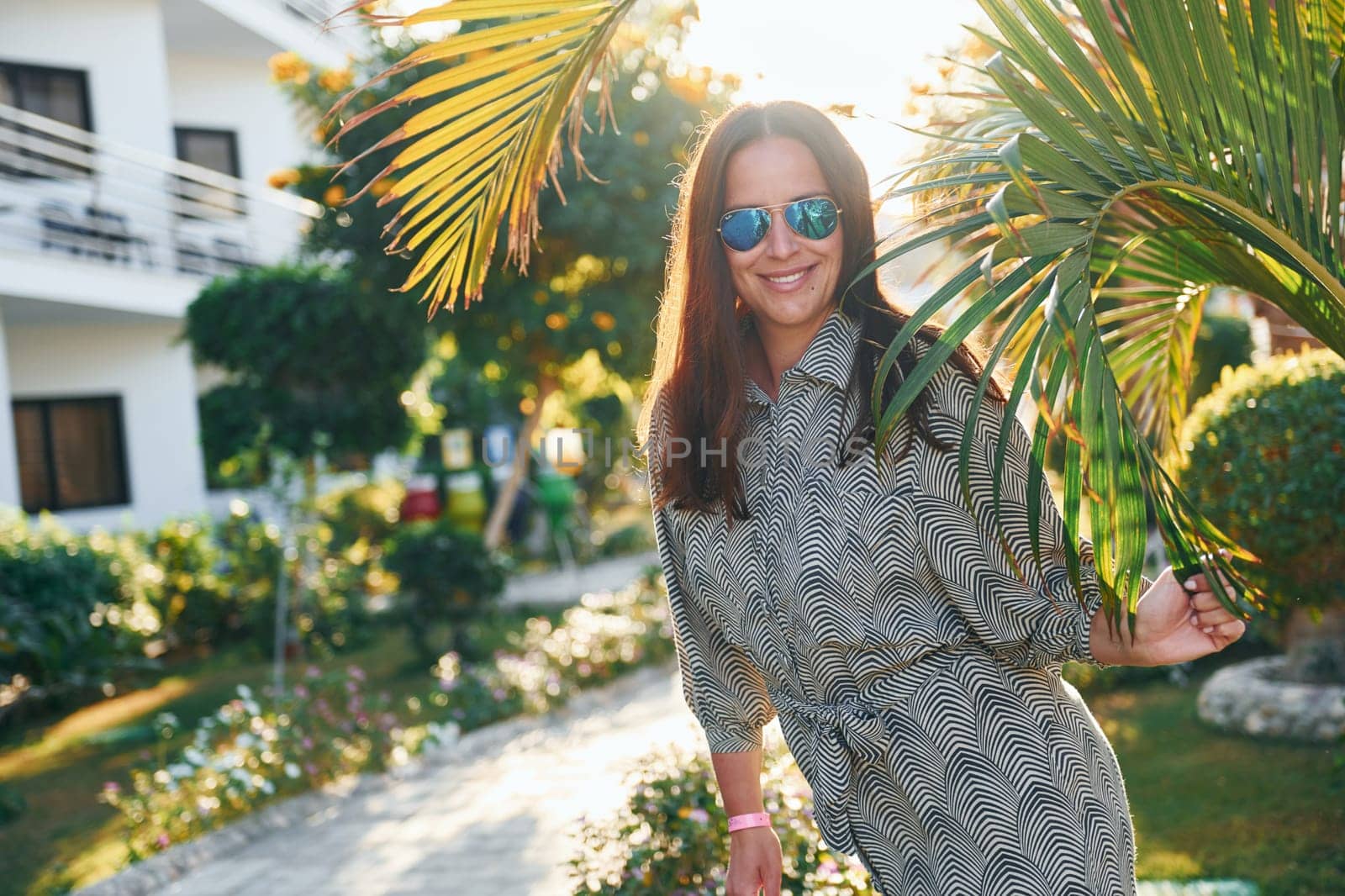 Happy mature woman is outdoors enjoying her vacation at sunny daytime by Standret