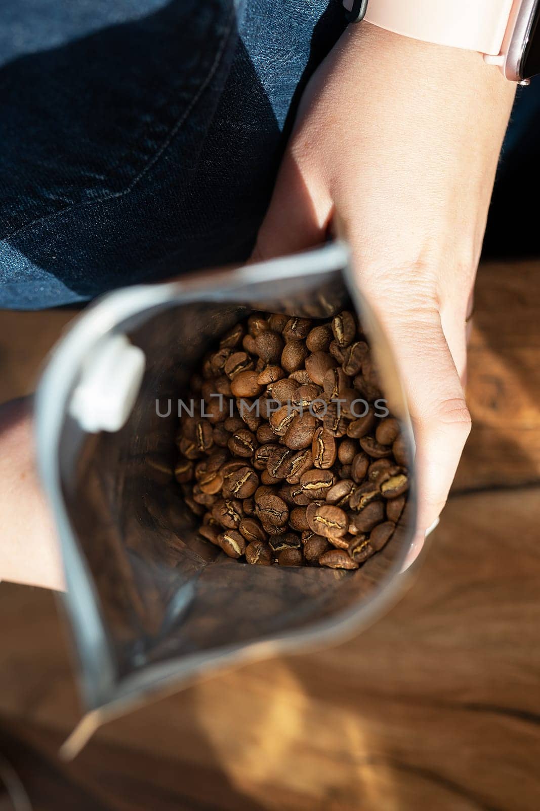 The roasted coffee bean is packaged in a bag that the barista holds in his hands. Top view, coffee preparation concept