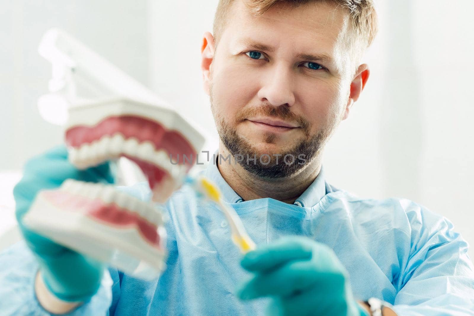 A model of a human jaw with teeth and a toothbrush in the dentist's hand by Lobachad