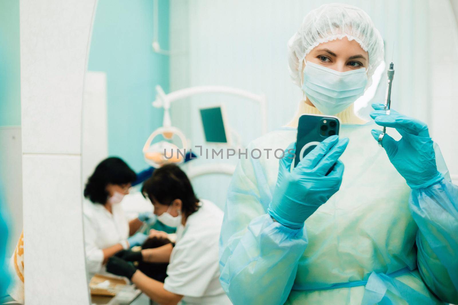 the dentist in a protective mask stands next to the patient and takes a photo after work.