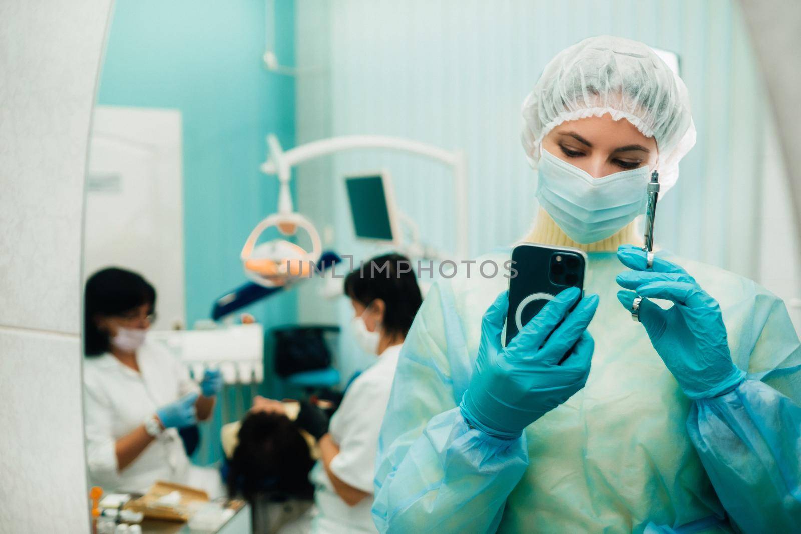 the dentist in a protective mask stands next to the patient and takes a photo after work by Lobachad