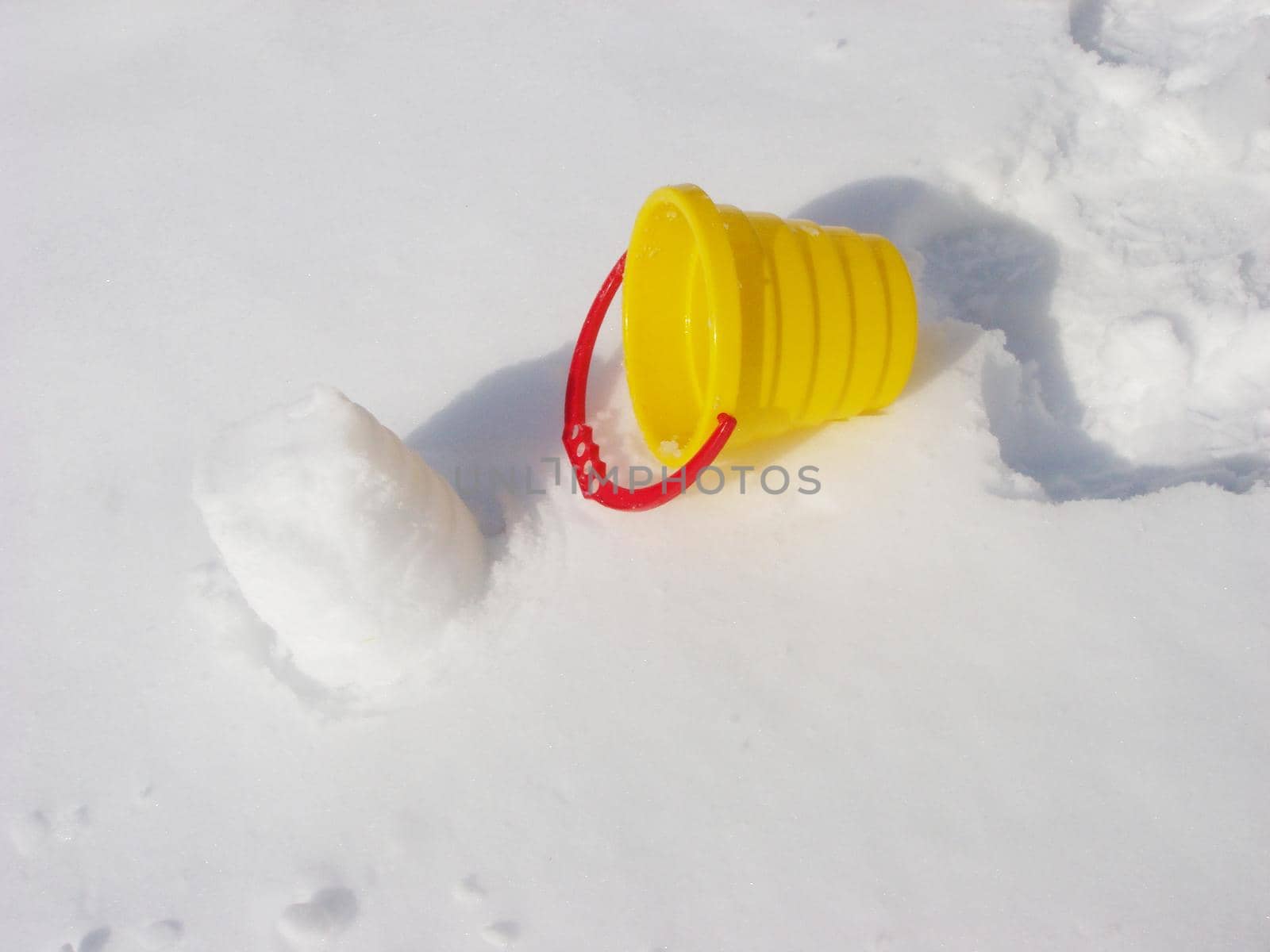 Toy bucket on snow isolated on white background/ Winter/ Horizontal. Colored children's toys in the snow.