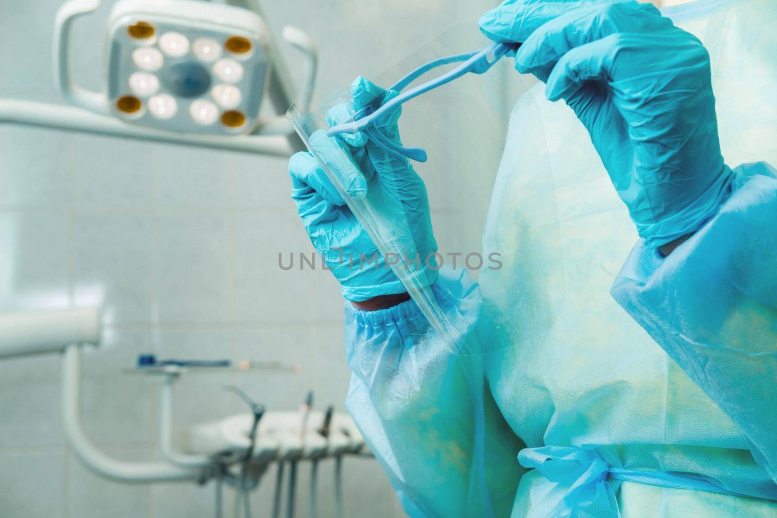 close up of a dentist's hands holding a protective plastic screen in his office.