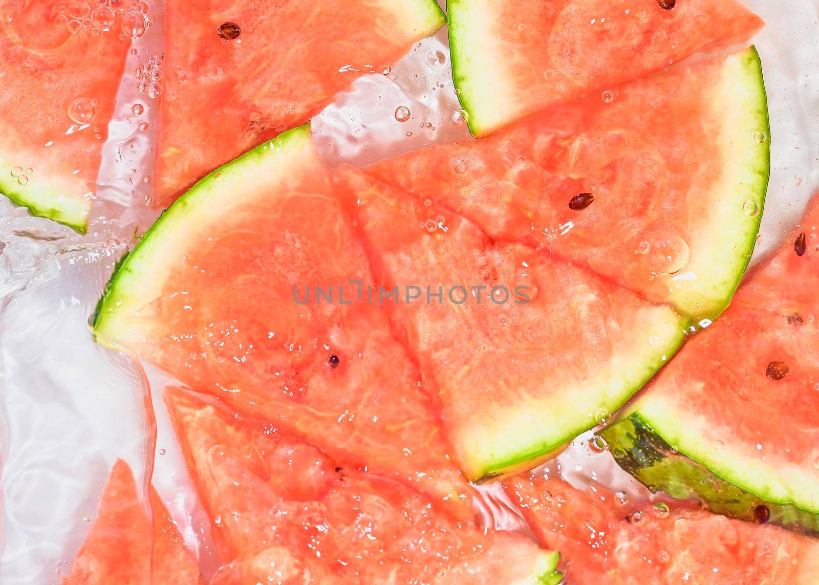 Slices of melon in water on white background. Melon close-up in liquid with bubbles. Slices of red ripe melon in water. Macro image of fruits in water.