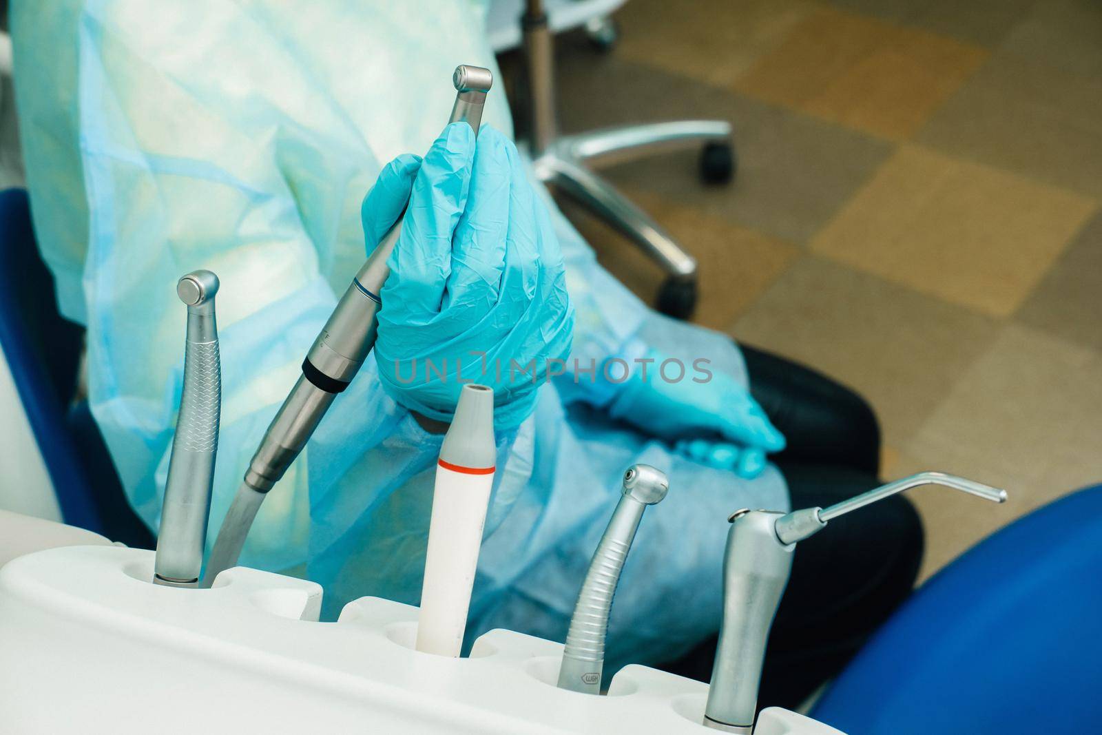 a dentist wearing gloves in the dental office holds a tool before working.