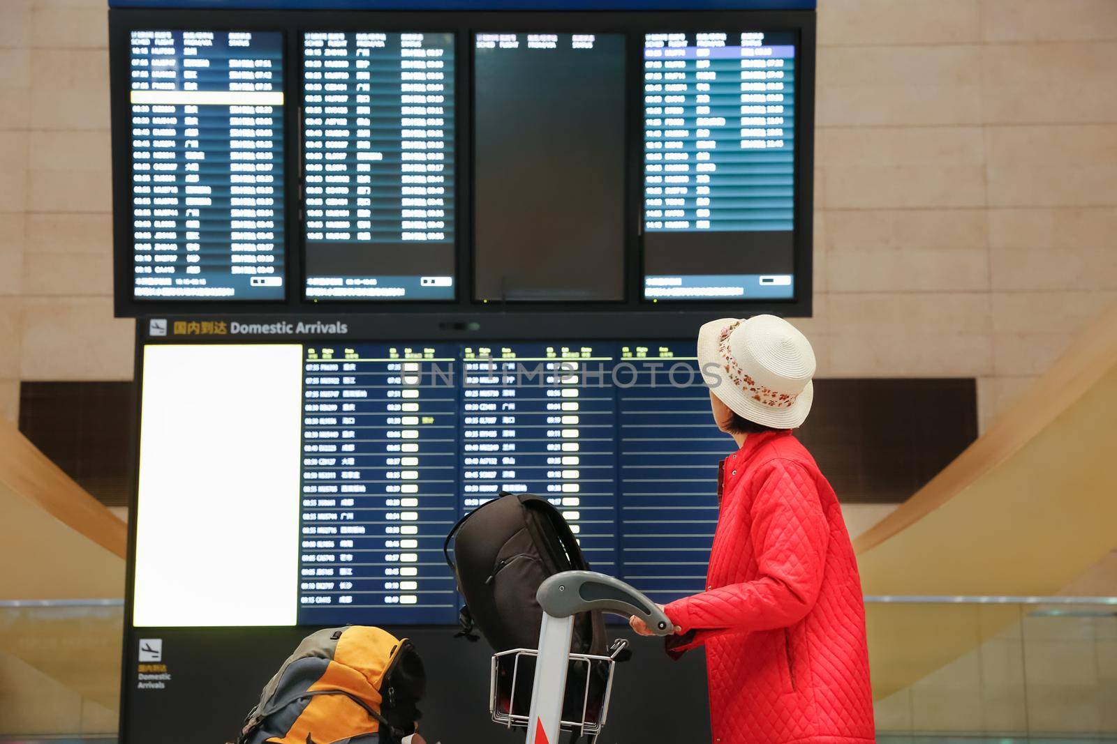 Tourist woman in China international airport looking at the flight information board by toa55