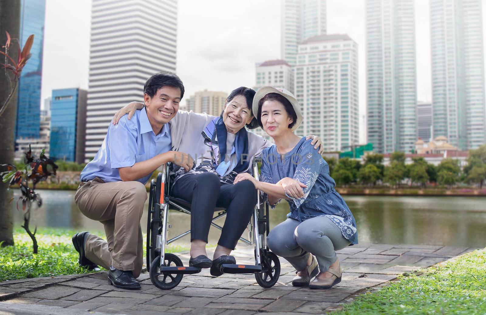 Son and daughter in law looking after elderly mother in backyard