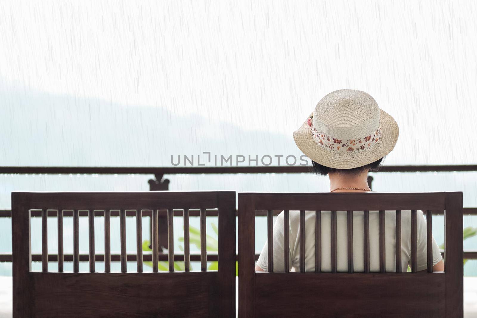 Rear view of middle aged woman on bench in rainy day