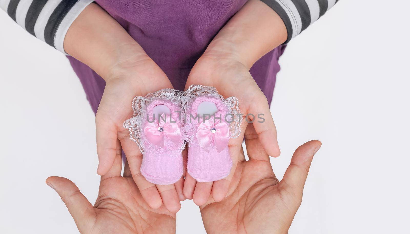 Dad and pregnant mom holding baby shoes, close up by toa55