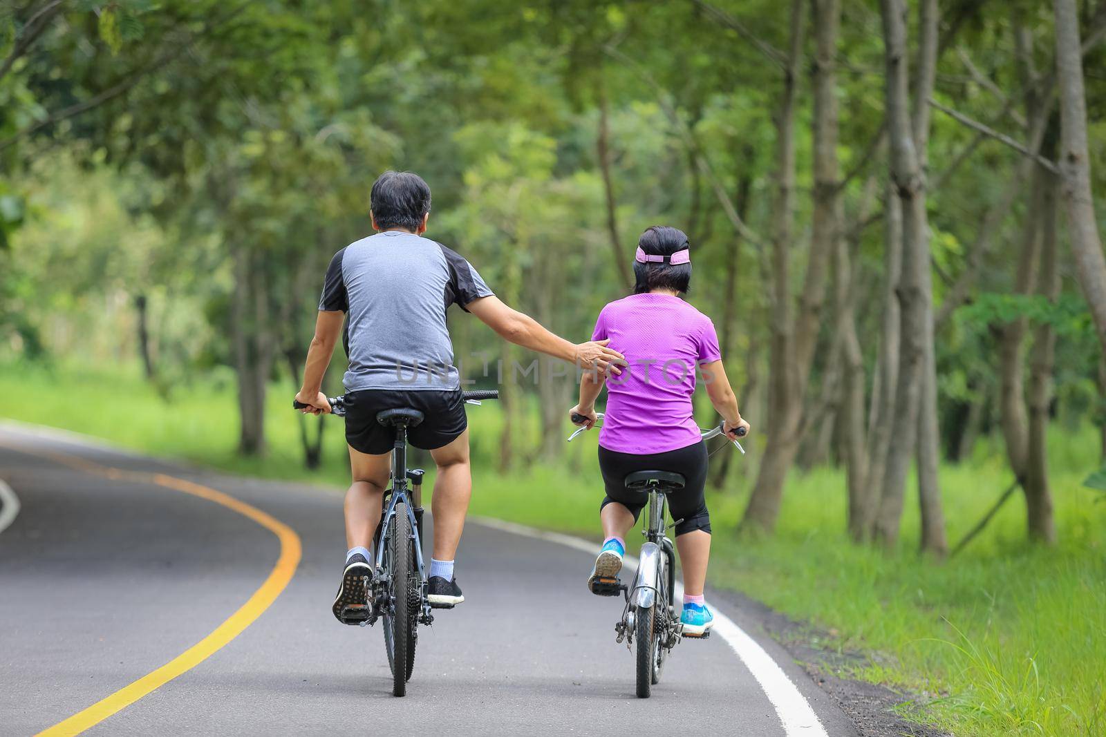 Middle aged couple relaxing exercise with bicycle in park