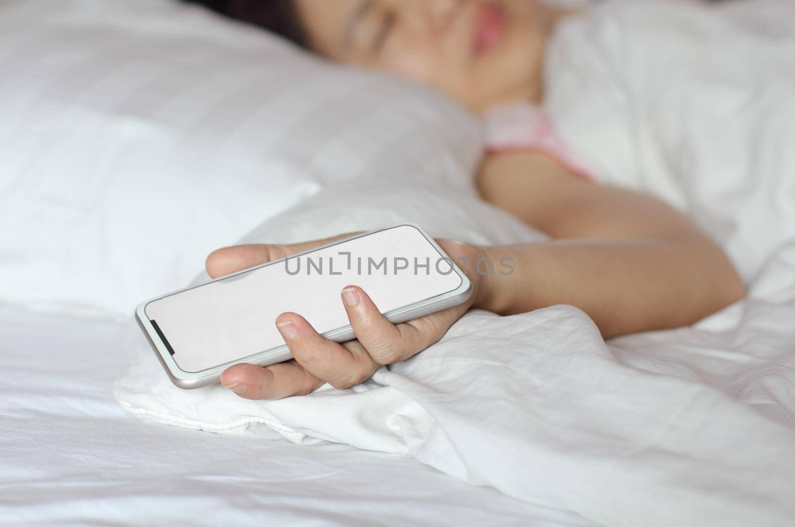 Woman sleeping in bed and holding a cell phone.