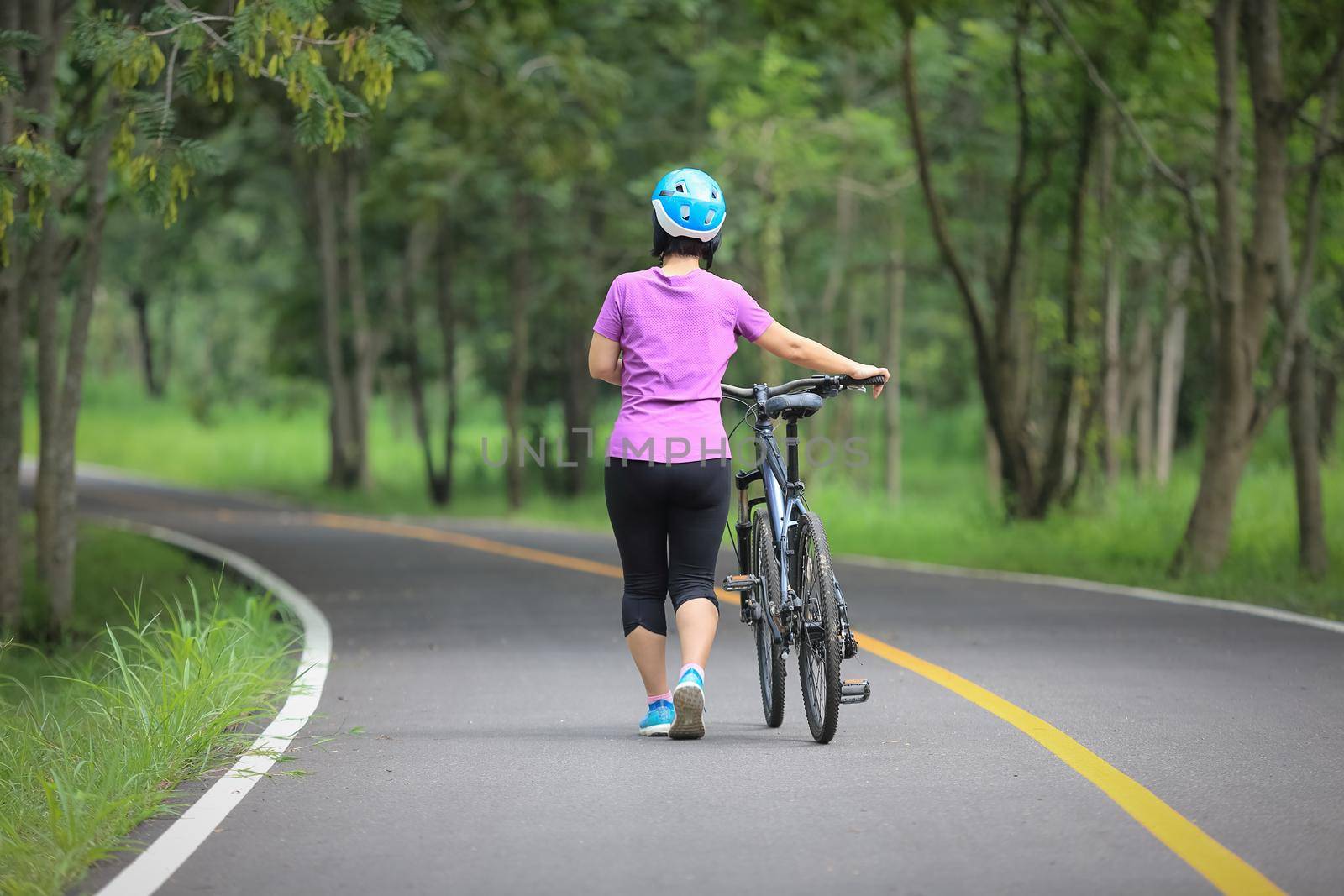 Middle aged relaxing exercise with bicycle in park