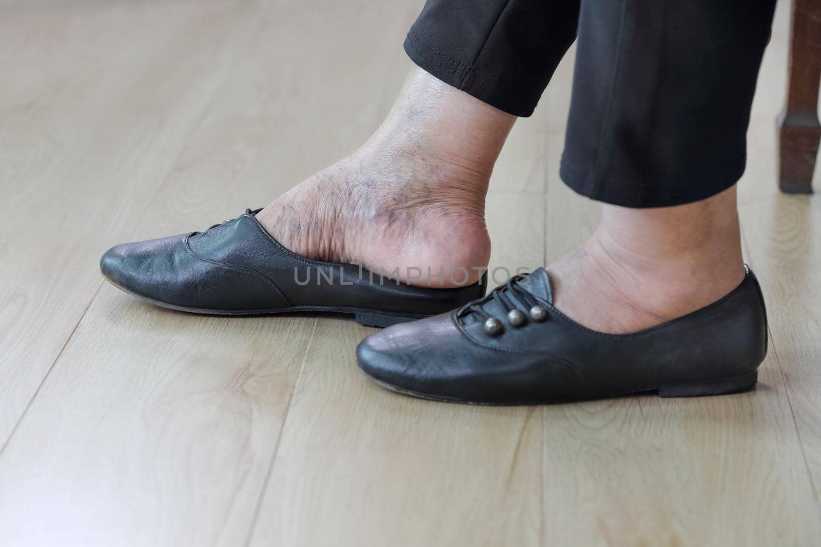 Elderly woman putting on shoes.