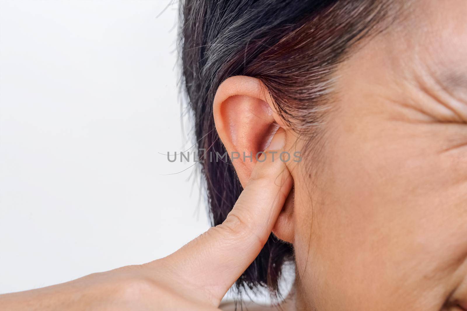 Senior woman closes ears with fingers to protect from loud noise , Isolated on white background