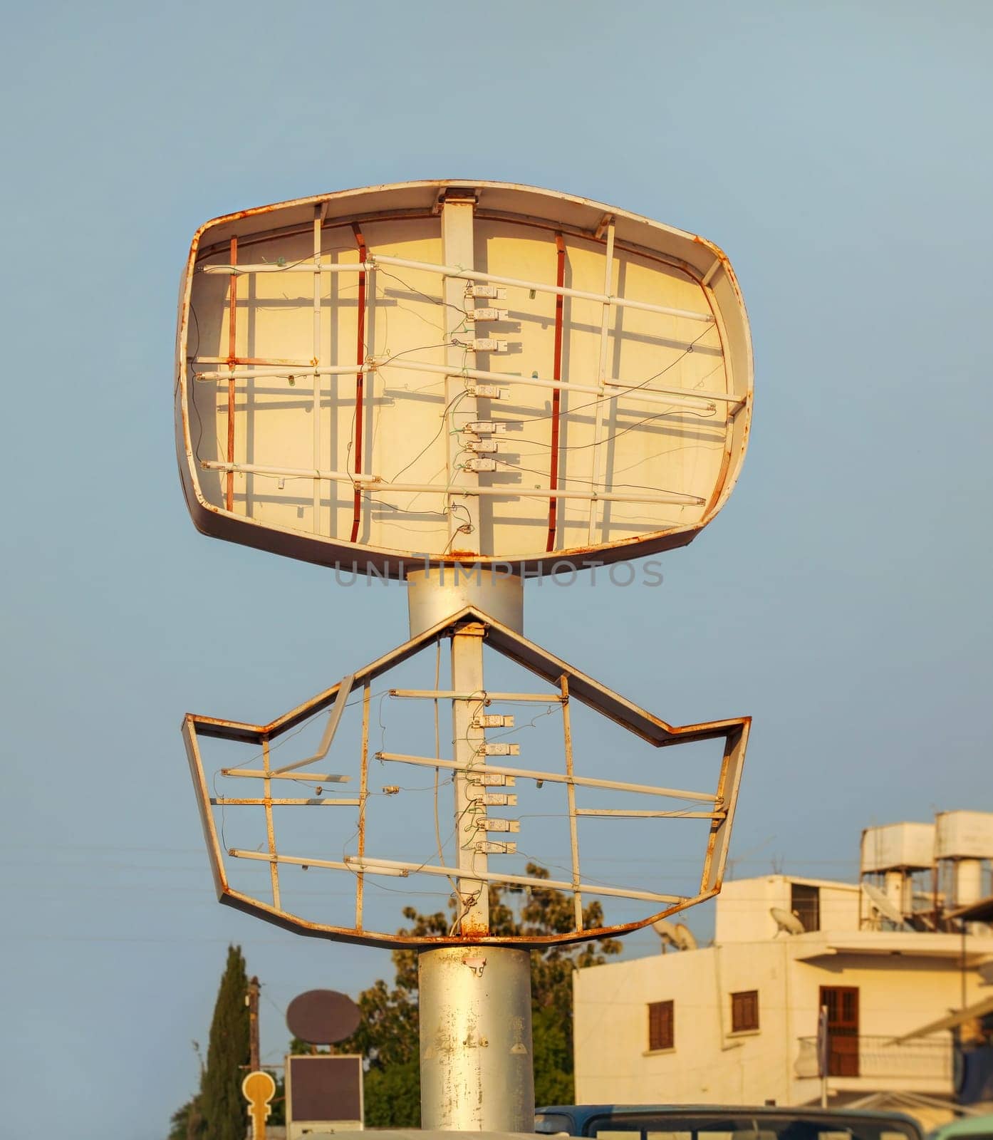 Empty neon advert sign, light tubes visible, lit by afternoon sun.