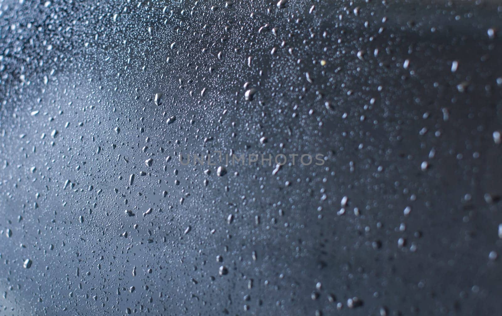Rear of car wet after being washed in carwash. Abstract "drops of water on glass" background.