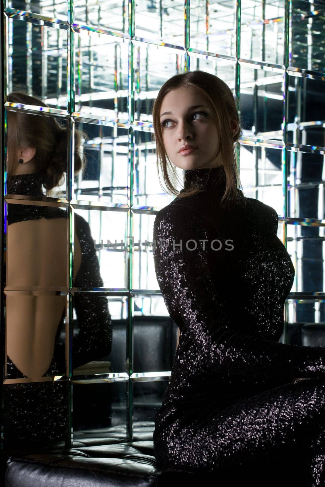 Full length portrait of beautiful young woman in long black dress near mirror