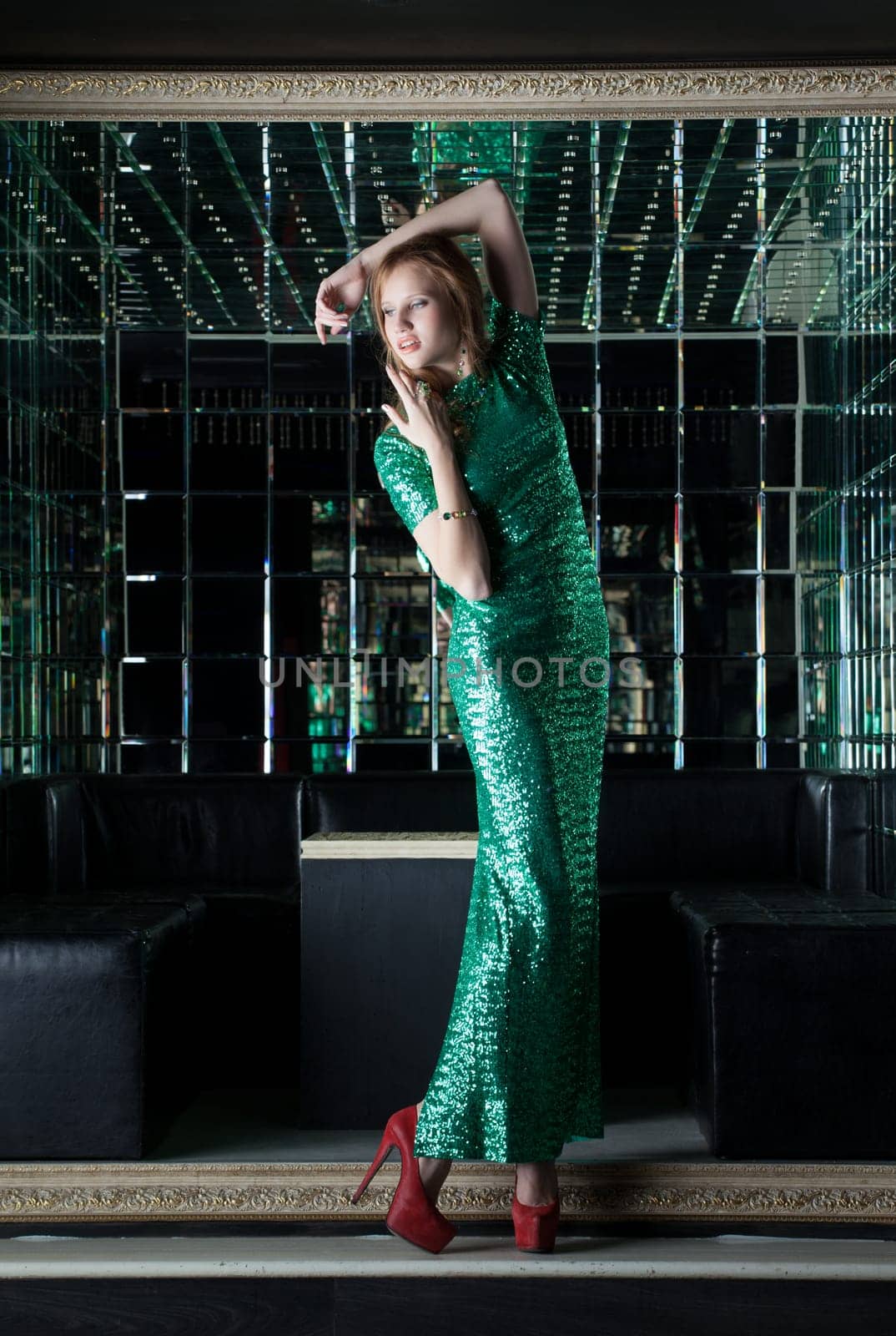 Young red woman in fashion green dress - mirror room of nightclub