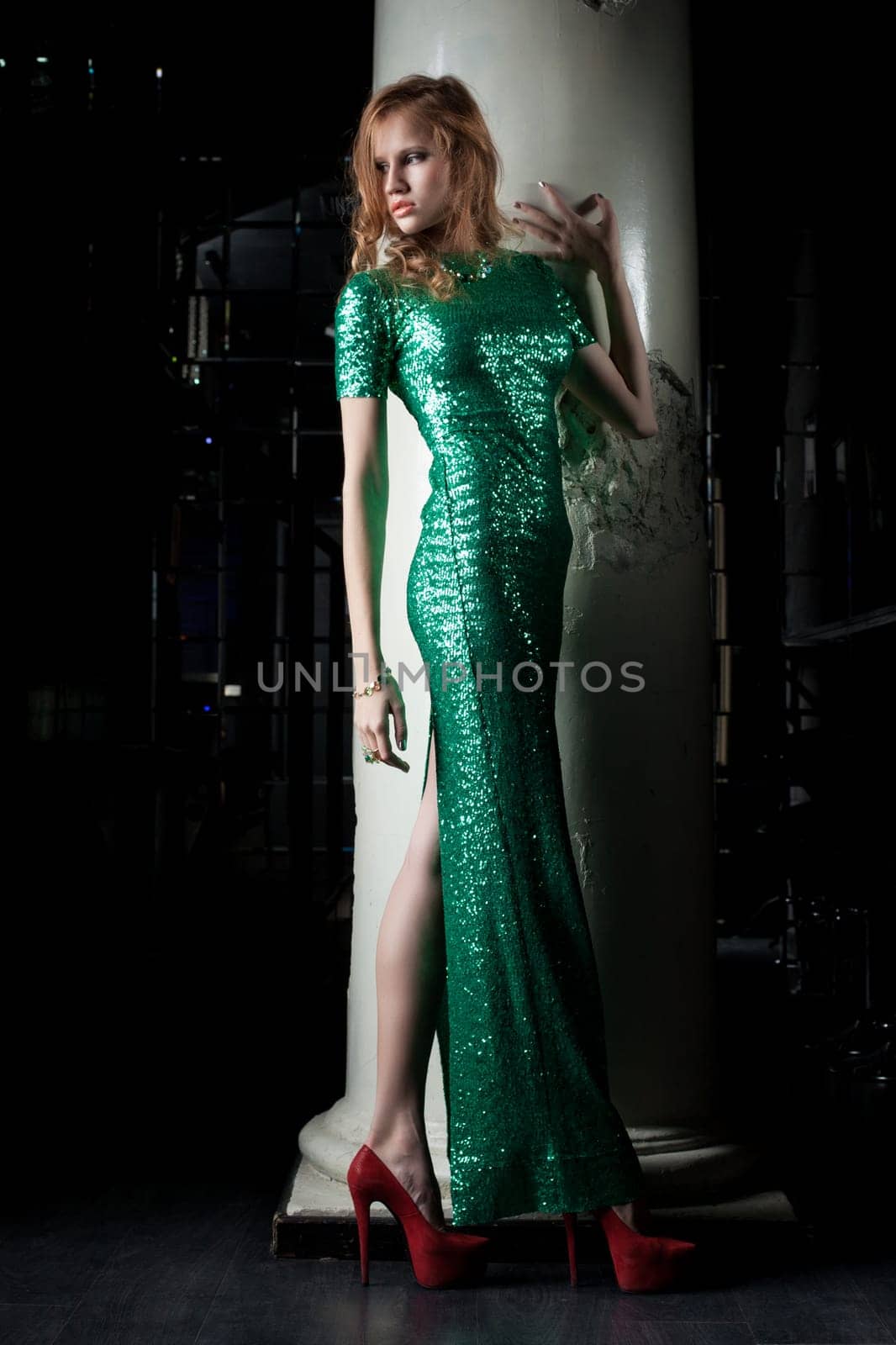 Full length portrait of young red woman in green dress in nightclub