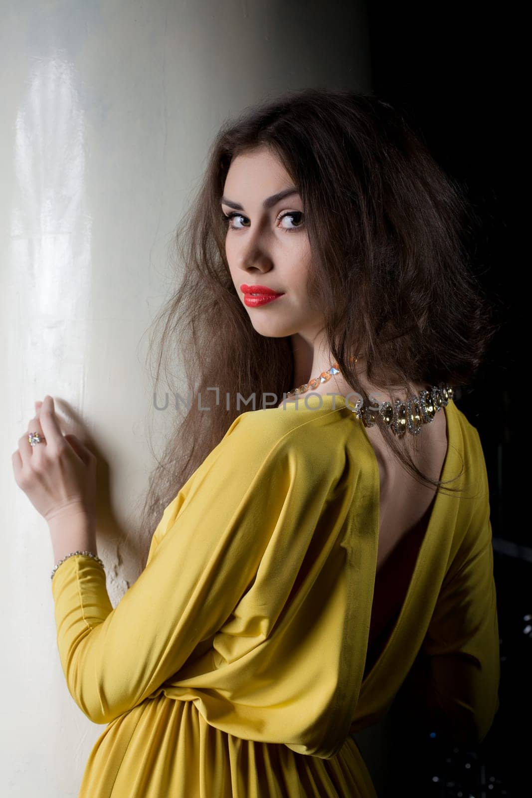 Portrait of beautiful brunette woman near column in fashion night club