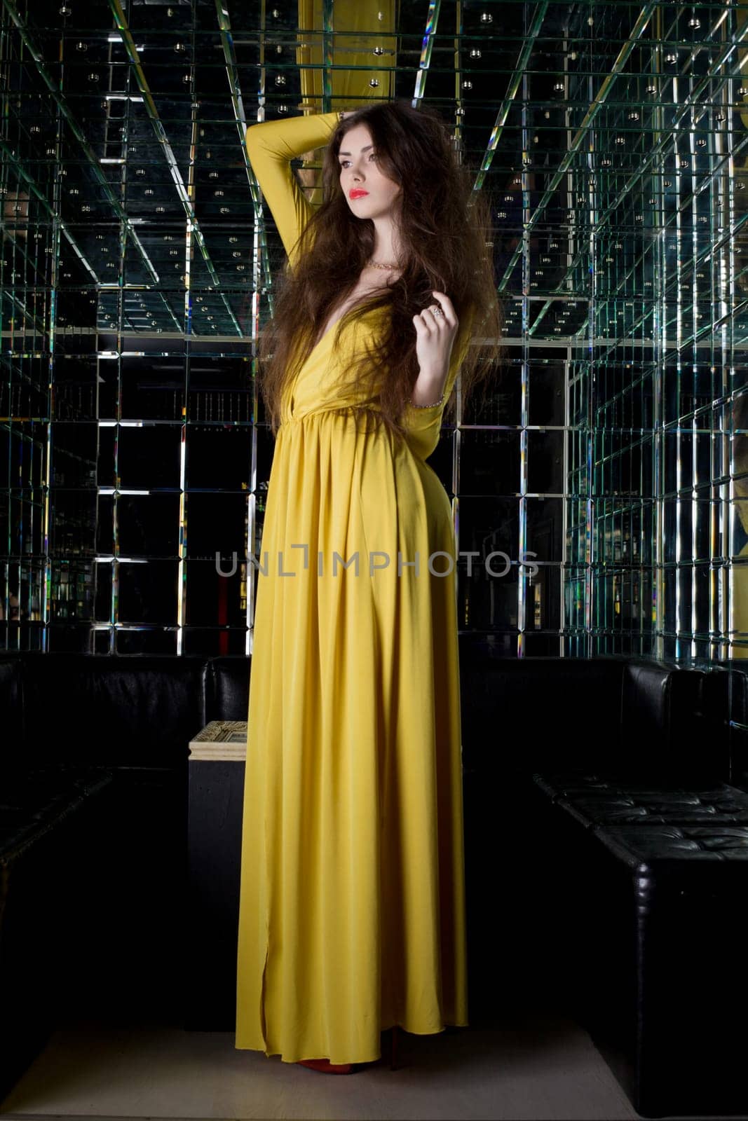 Full length portrait of pretty brunette woman in long fashion dress -- night club interior