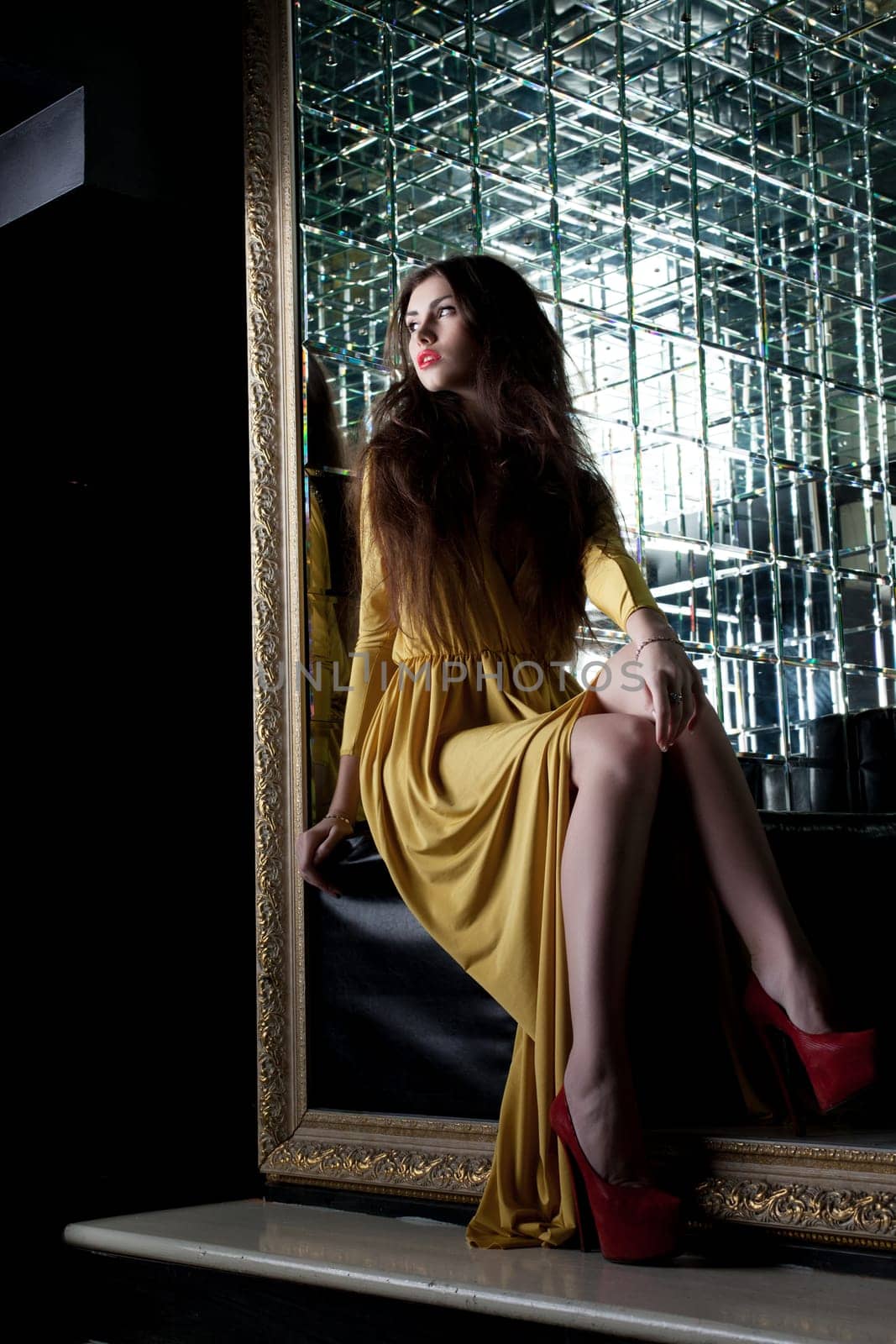 Full length portrait of brunette young woman in long yellow dress in club