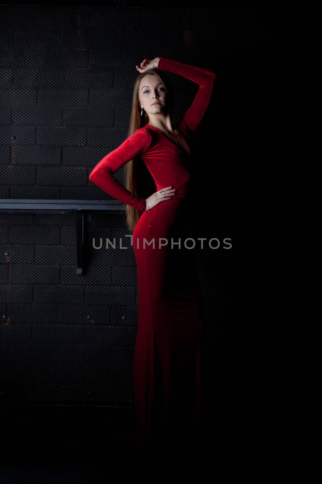 Full length portrait of beautiful woman in red long dress in dark night club