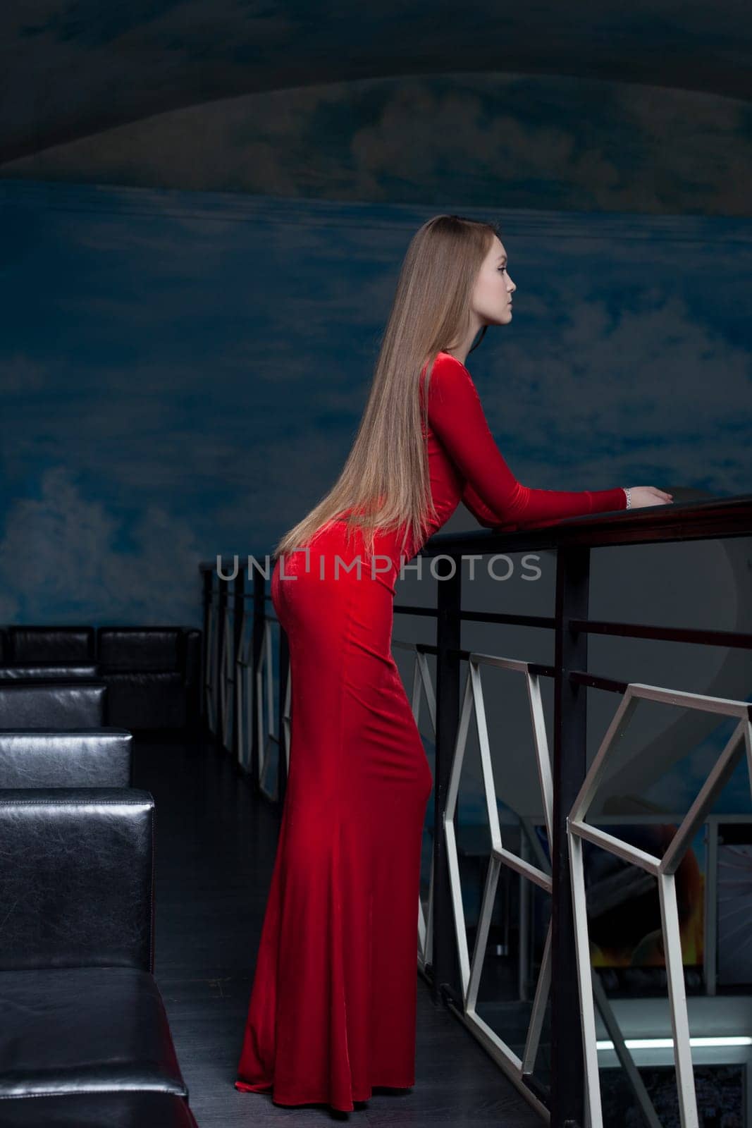 Full length portrait of beautiful woman in red long dress in club