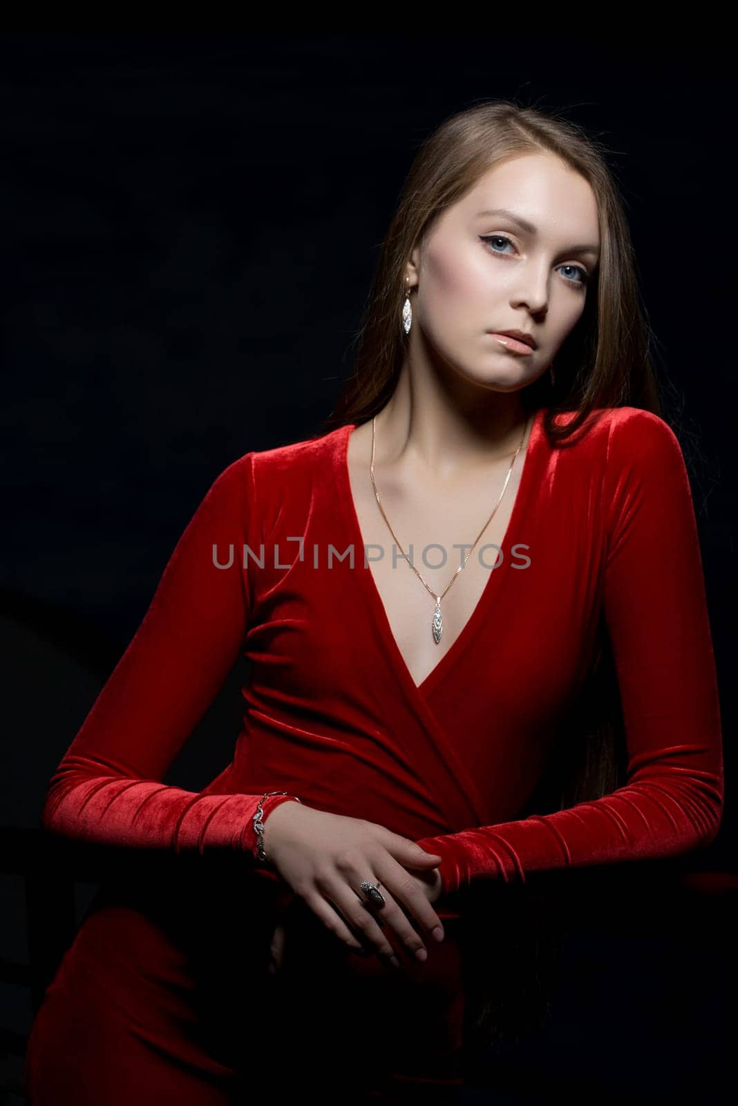 Portrait of beautiful young woman in red dress in dark nightclub