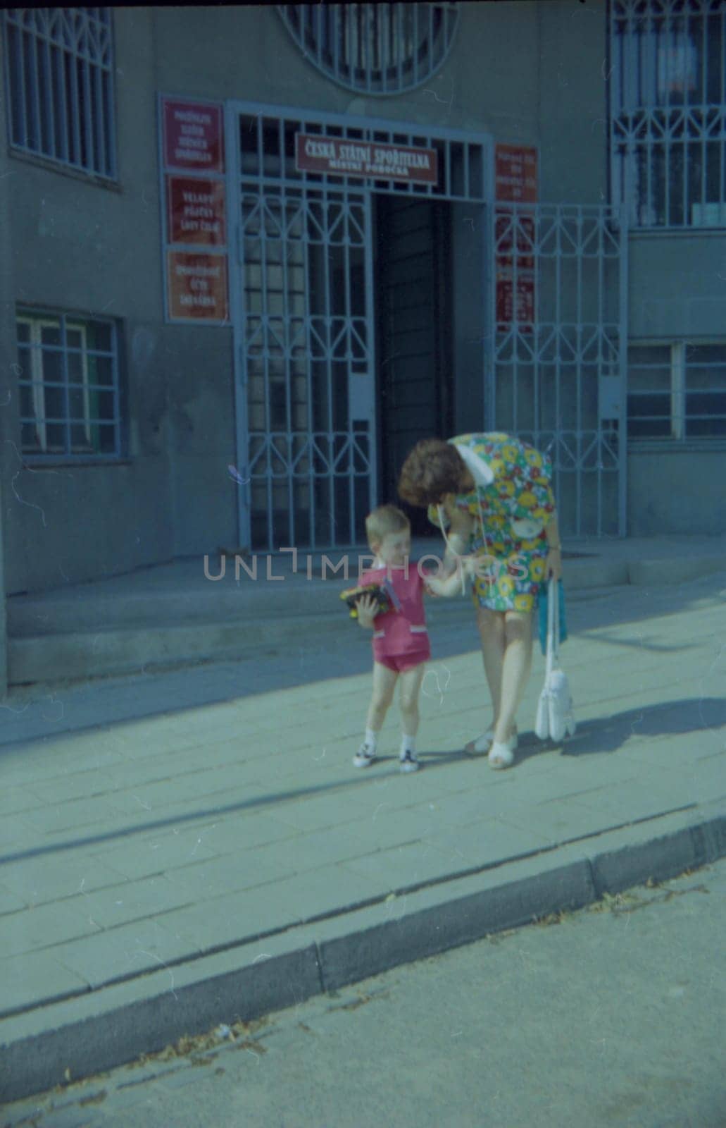 Retro photo shows mother and son with toy outdoors. by roman_nerud