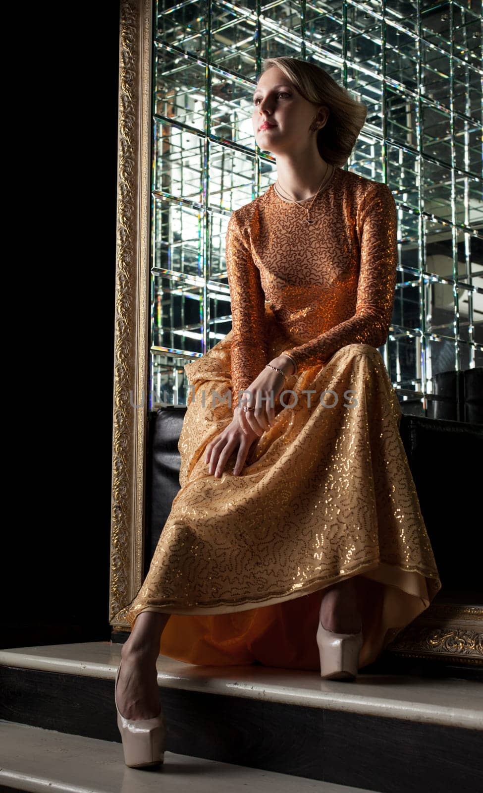 Charming blonde posing in fashionable golden dress