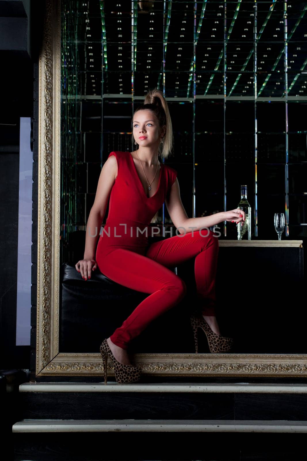 Full length portrait of young woman sitting on sofa in nightclub