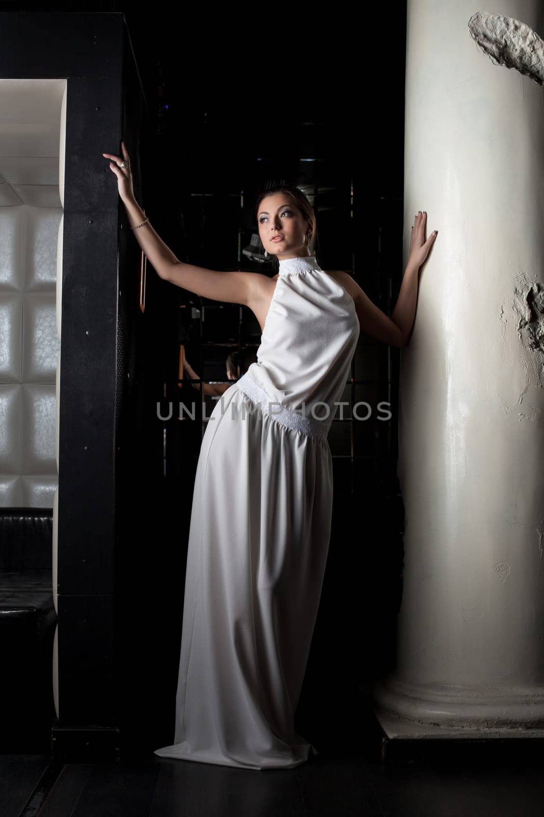 Portrait of pretty brunette young woman near column in fashion cloth