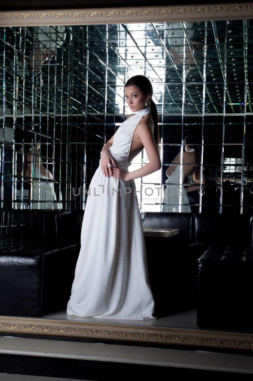Full length portrait of brunette woman in white dress in club