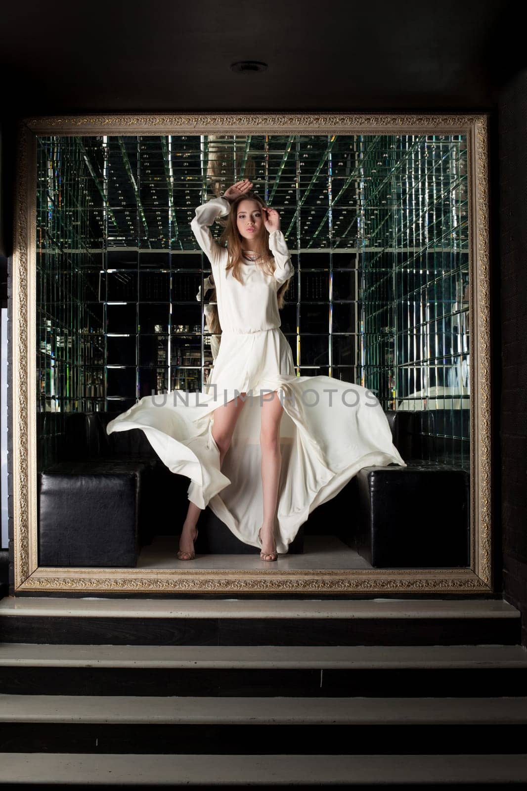 Full length portrait of beautiful young woman in white dress in club