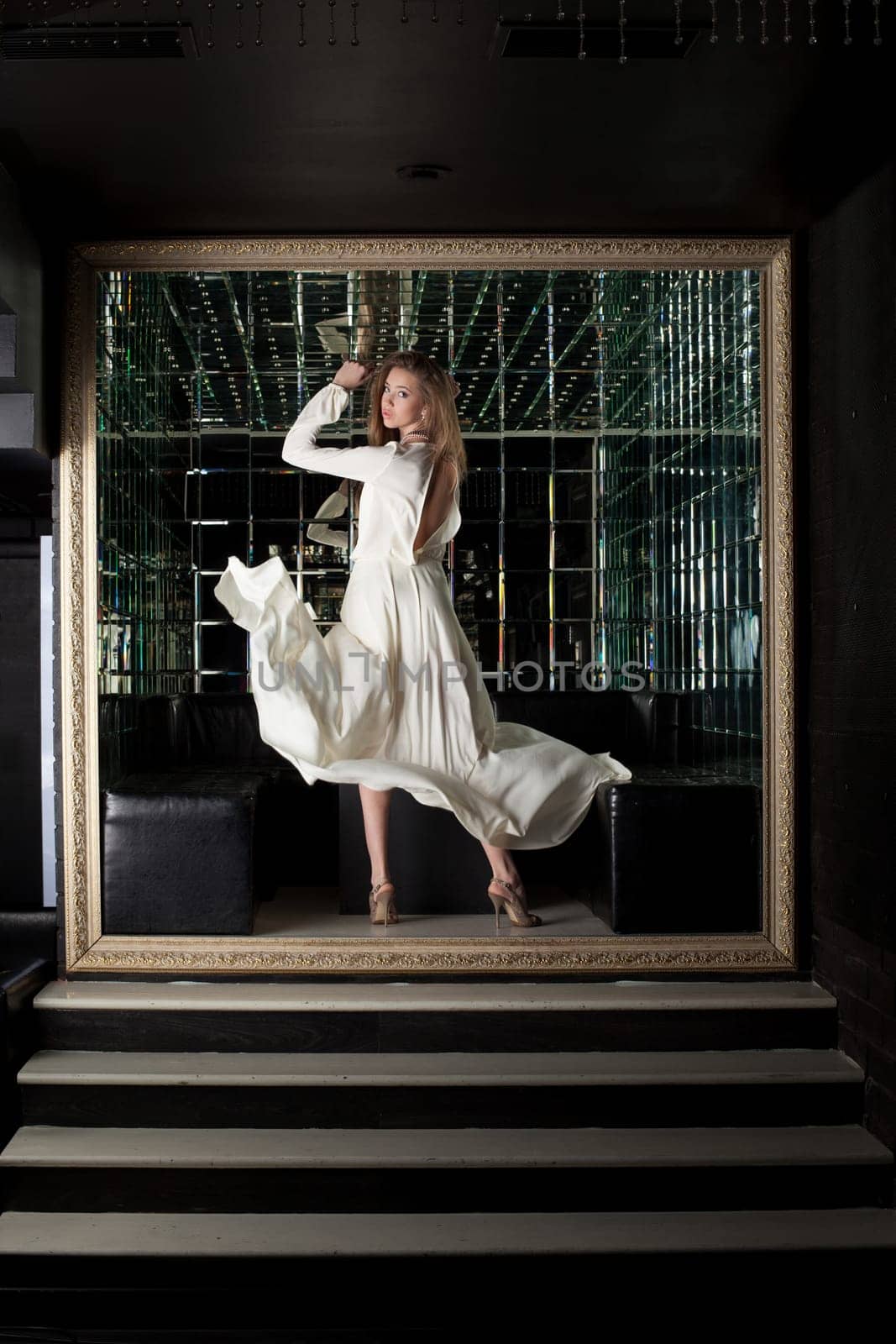 Full length portrait of pretty oung woman model in white dress in club