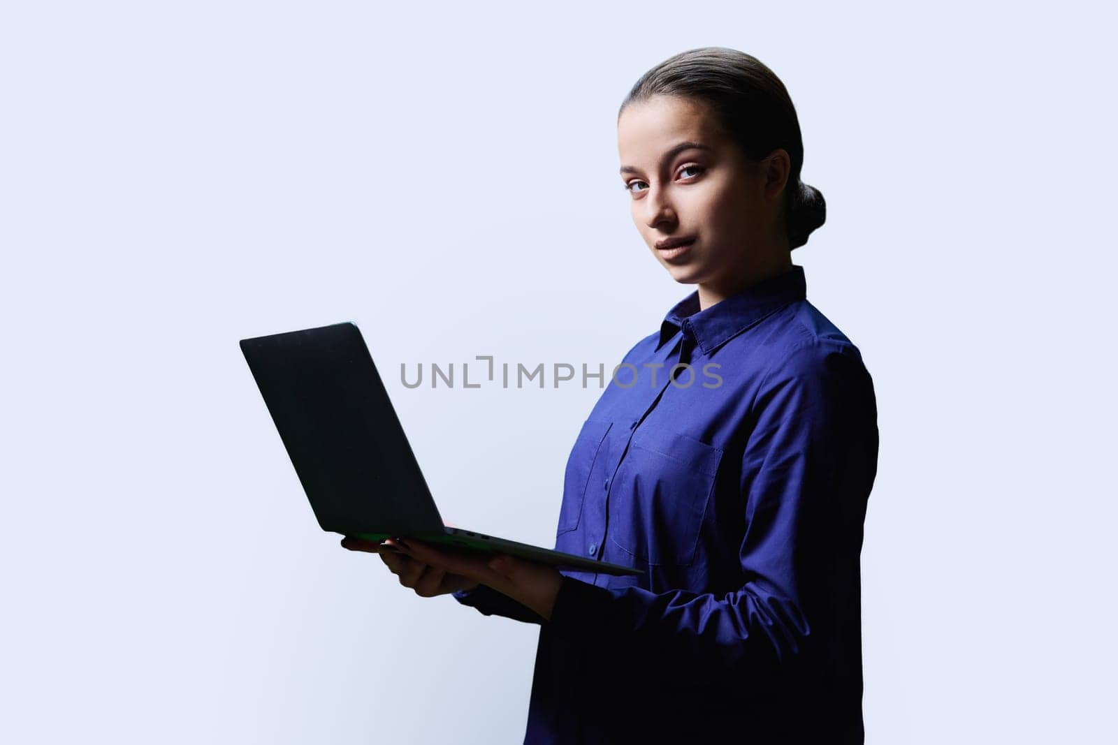 Teenage girl high school student using laptop looking at camera on white background. Education, learning, technology, adolescence concept