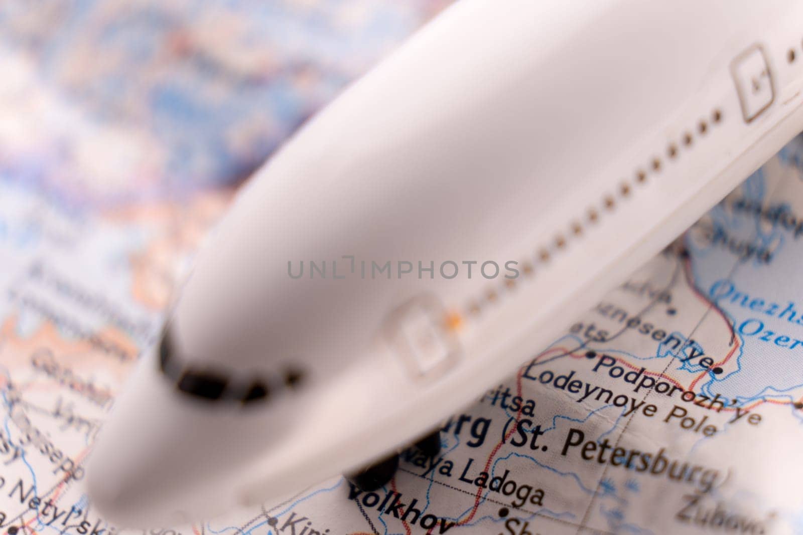 Close up detail of a miniature passenger airplane on a colorful map focusing on St. Petersburg Russia through selective focus, background blur.
