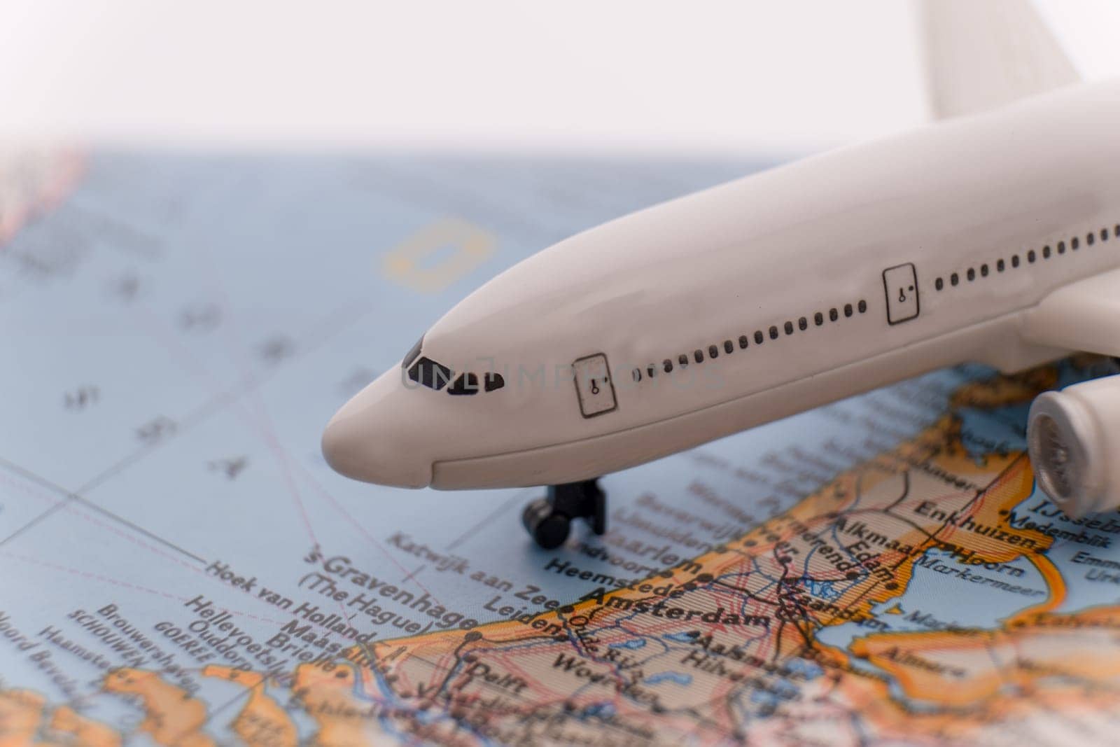 Close up detail of a miniature passenger airplane on a colorful map focusing on Amsterdam Netherlands through selective focus, background blur.