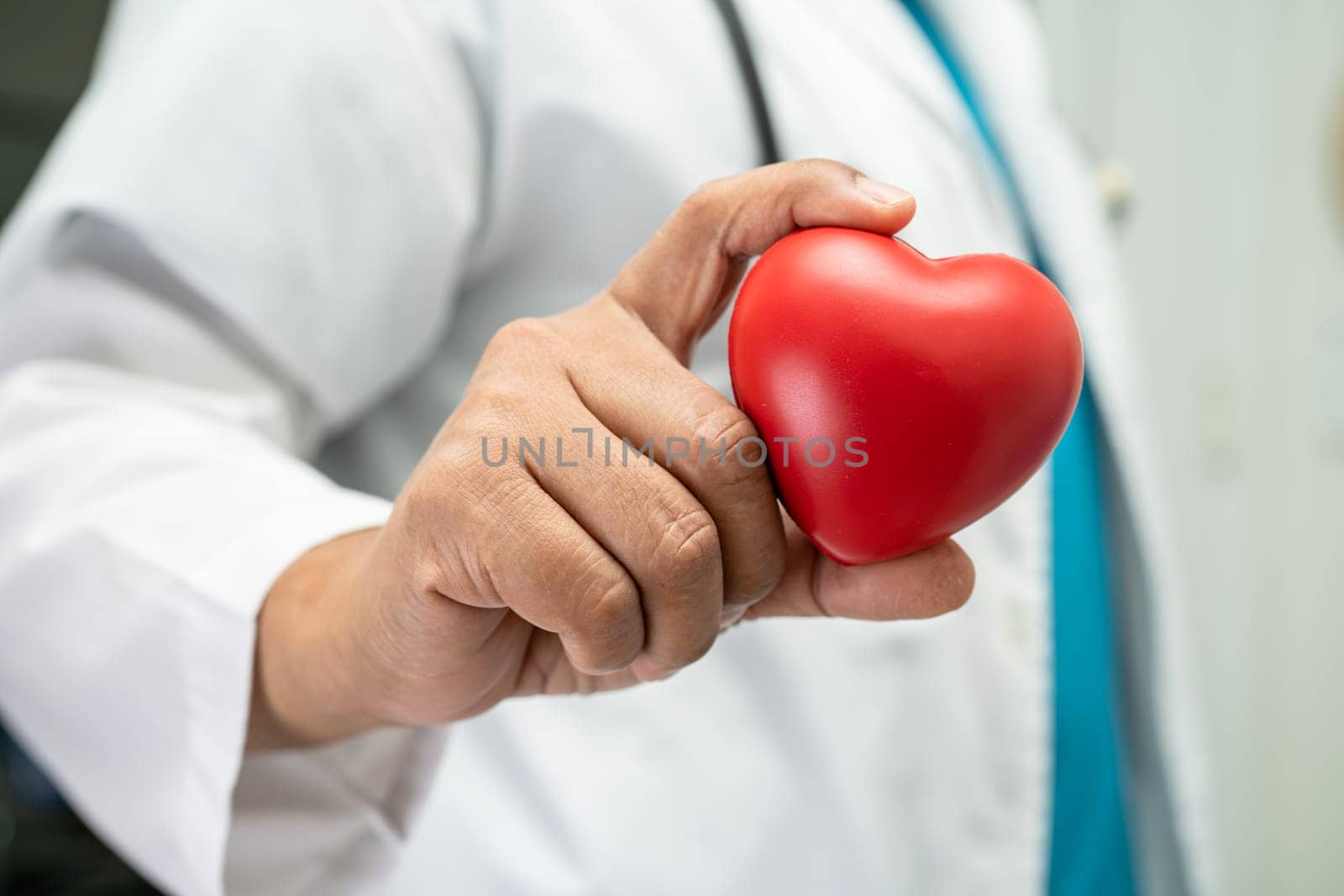 Doctor holding a red heart in hospital ward, healthy strong medical concept.