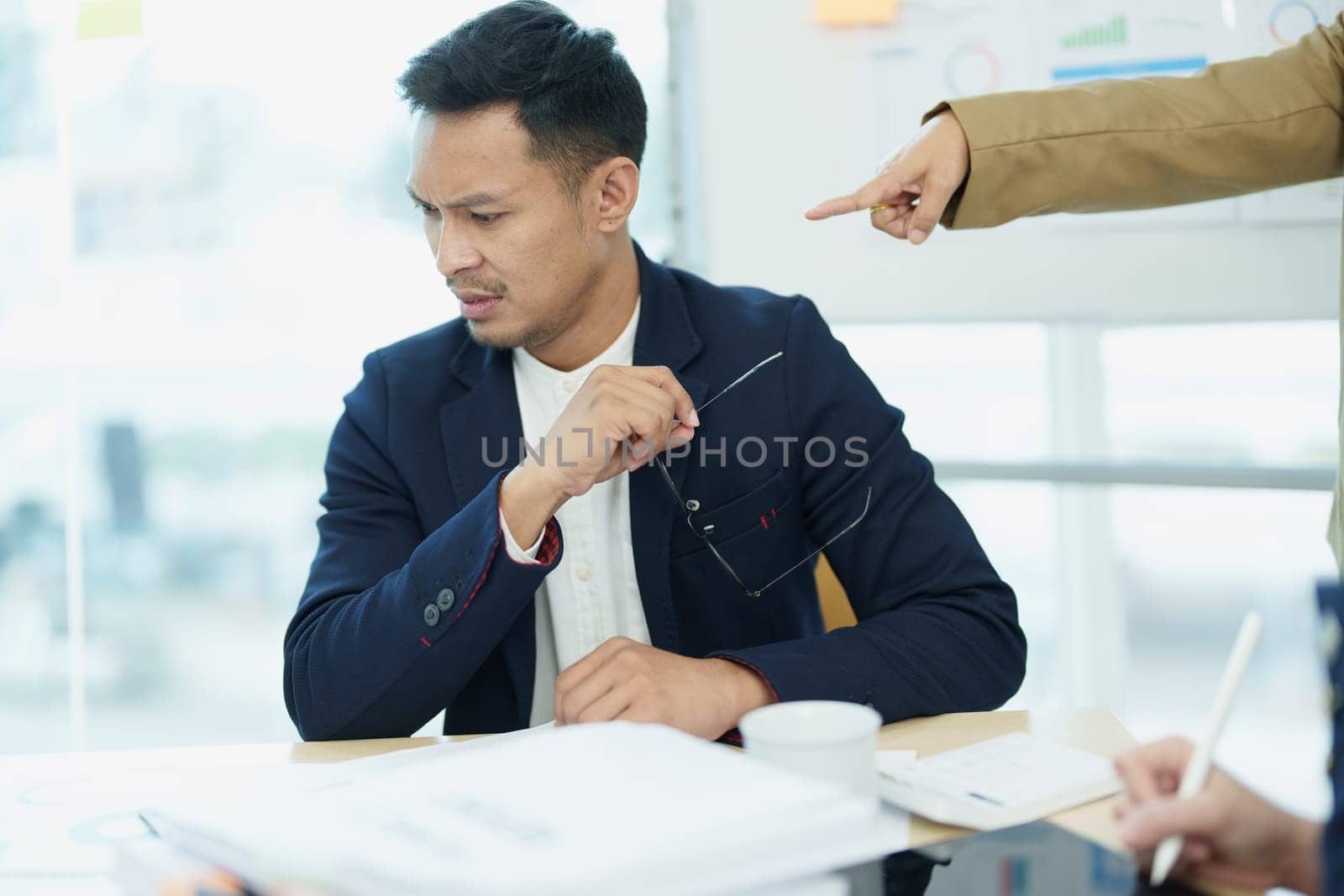 An image of an Asian male employee looking worried and sad about being scolded by his boss for failing to meet sales targets, concept of disappointment and failure in his career.