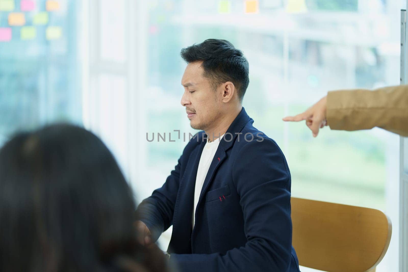 An image of an Asian male employee looking worried and sad about being scolded by his boss for failing to meet sales targets, concept of disappointment and failure in his career.