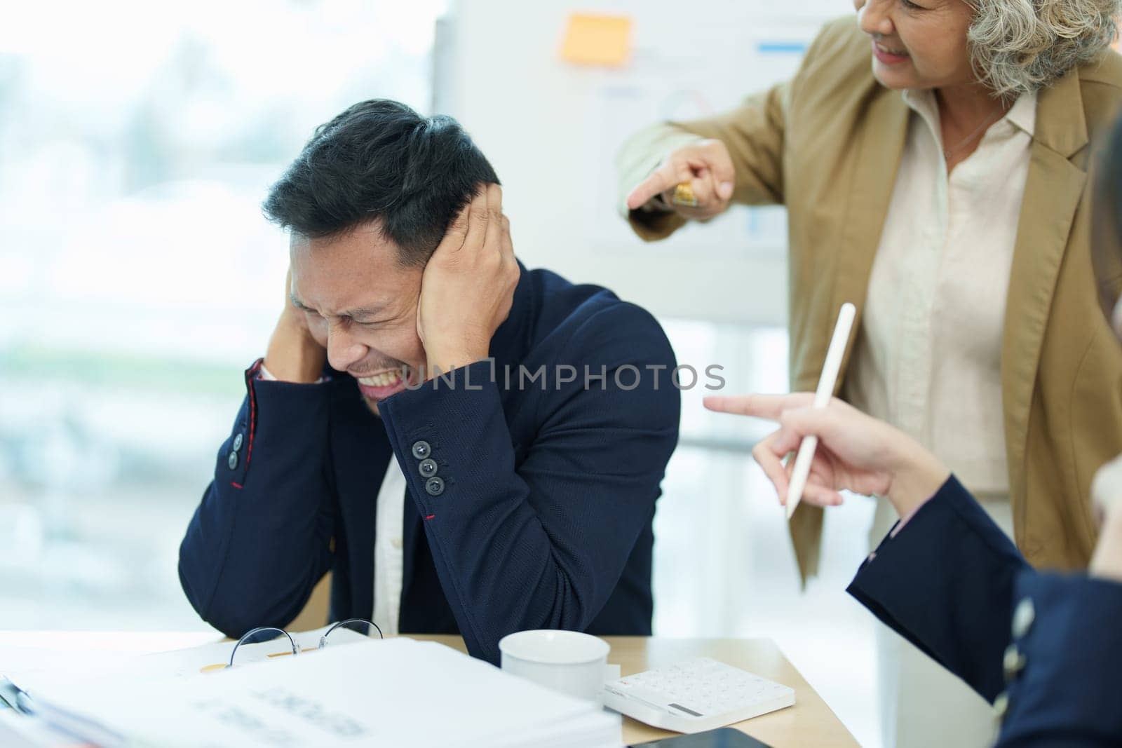 An image of an Asian male employee looking worried and sad about being scolded by his boss for failing to meet sales targets, concept of disappointment and failure in his career by Manastrong