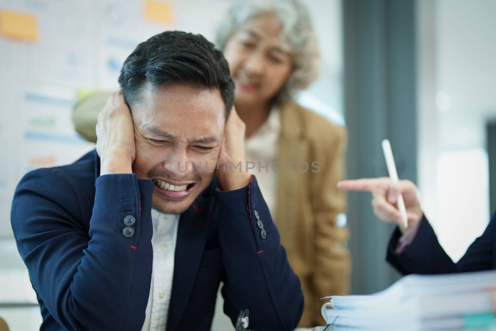 An image of an Asian male employee looking worried and sad about being scolded by his boss for failing to meet sales targets, concept of disappointment and failure in his career.